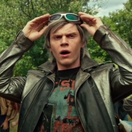 Evan Peters while holding his glasses is looking at something. 